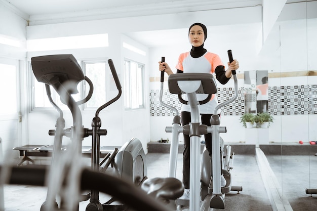 Muslimische Frauen im Fitnessstudio machen Cardio-Übungen auf einem statischen Crosstrainer