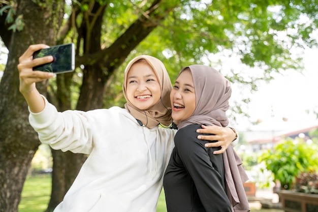 muslimische Freundin, die während des Sports mit ihrem Smartphone Selfie oder Videoanrufe im Freien macht