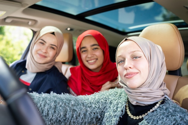 Muslimische Freundinnen, die einen Roadtrip genießen, der im Urlaub im Auto in hoher Qualität unterwegs ist