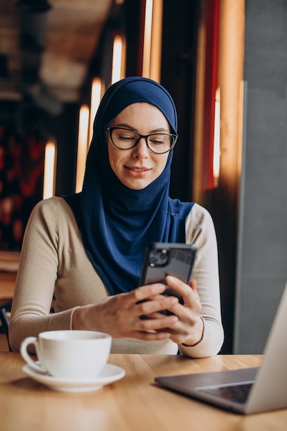 Muslimische Geschäftsfrau, die in einem Café am Computer arbeitet