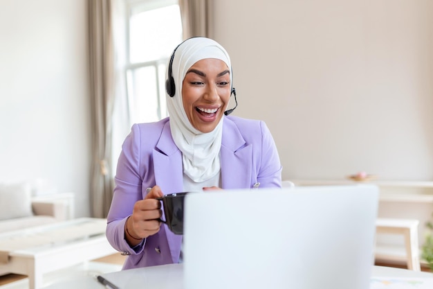 Muslimische Geschäftsfrau mit Headsets, die im Büro mit dem Computer arbeiten