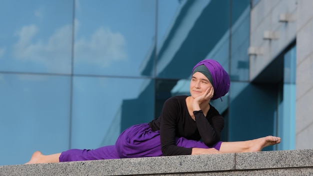 Muslimische islamische arabische syrische Inderin im Hijab Mädchen Yogi Sportlerin Turnerin sitzt auf Schnur gute Dehnungssport Yoga Trainingsstrecke im Stadtgebäude Hintergrund Flexibilitätskonzept