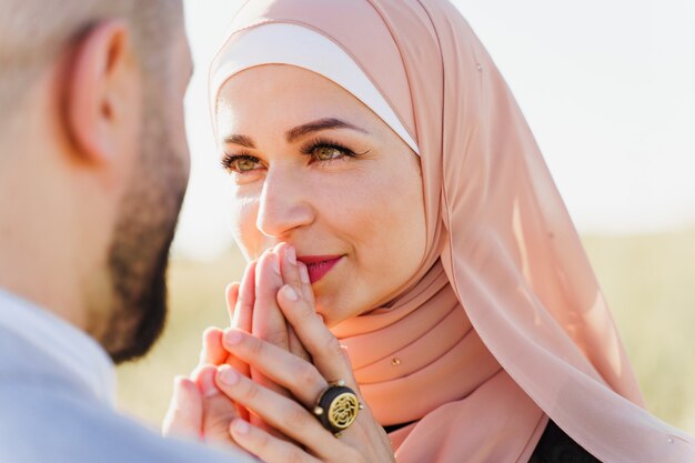 Muslimische Liebesgeschichte Nahaufnahme. Gemischtes Paar lächelt und umarmt auf den grünen Hügeln.