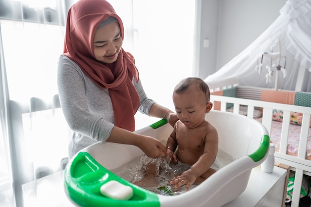 Muslimische Mutter, die kleinen Jungen in der Badewanne wäscht