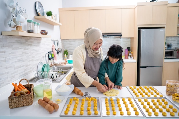 Muslimische Mutter während der Ramadan-Aktivität mit ihrer Tochter, die zusammen einen Nastar-Kuchen backt