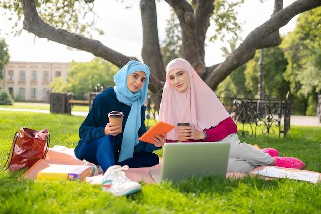 Muslimische Studenten. Schöne muslimische Studenten, die Hijab tragen, genießen eine Pause draußen in der Nähe der Universität?