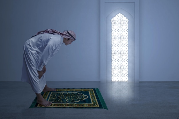 Muslimischer Mann mit Keffiyeh mit Agal in Gebetsposition Salat auf dem Gebetsteppich