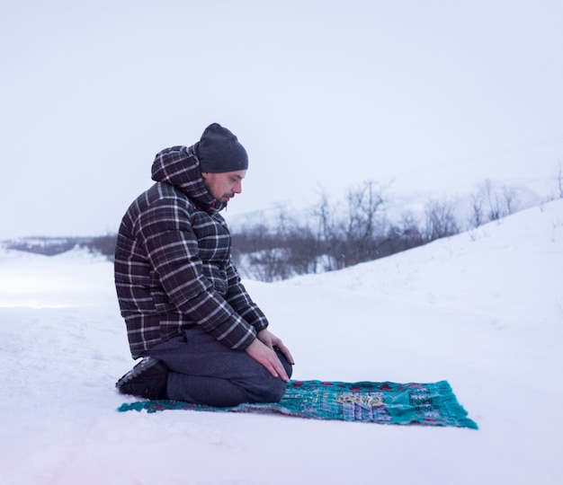 Muslimischer Reisender, der im Winterberg betet