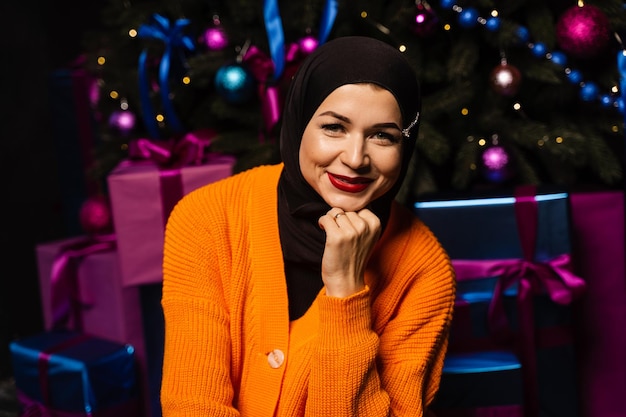 Muslimisches Mädchen im schwarzen Hijab träumt von einem Geschenk im Neujahrsurlaub. Weihnachtsfeier der islamischen Religion.