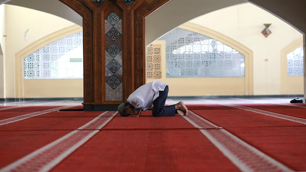 Muslimisches Manngebet für Gott in der Moschee Der erwachsene asiatische Muslim ist auf den Knien und betet