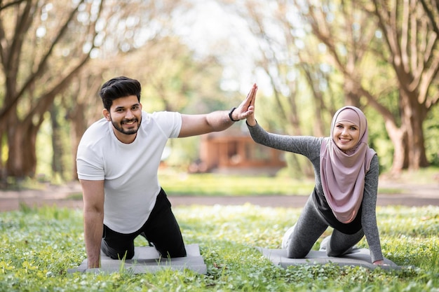 Muslimisches Paar gibt High Five, während es in Planke steht