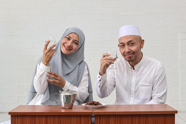 Muslimisches Paar zur Iftar-Zeit, das Mineralwassergetränk zum Frühstück zeigt. Fastenmonat Ramadan.