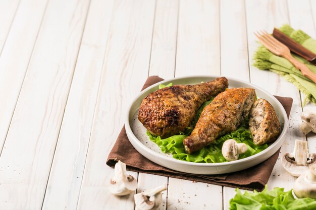 Muslo de pollo frito relleno de champiñones plato plano con hoja de lechuga en madera clara.