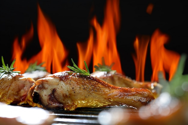 Muslo de pollo a la parrilla sobre la parrilla en llamas