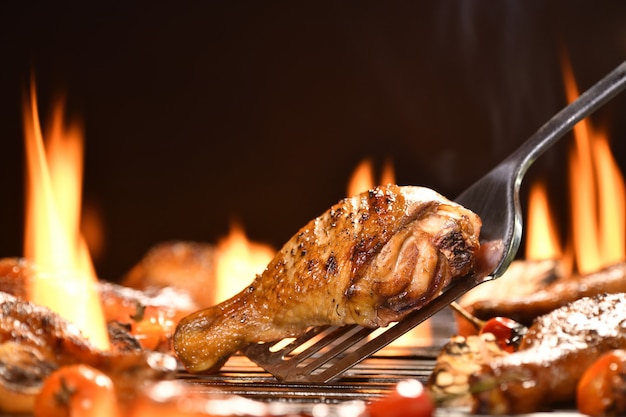 Muslo de pollo a la parrilla con varias verduras a la parrilla en llamas