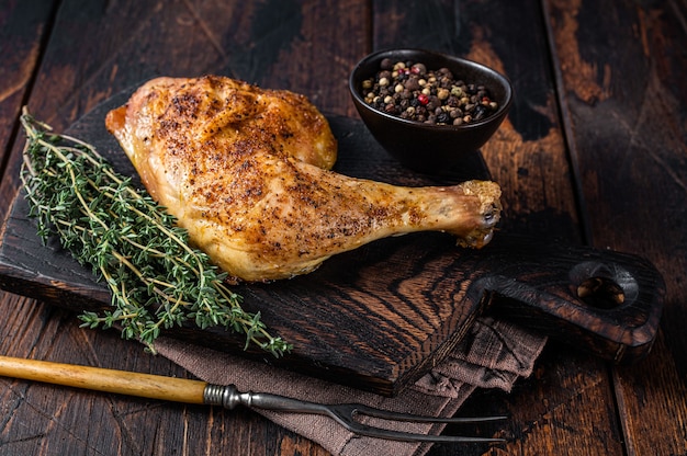 Muslo de pollo a la plancha sobre una tabla de madera. Fondo de madera oscura. Vista superior.