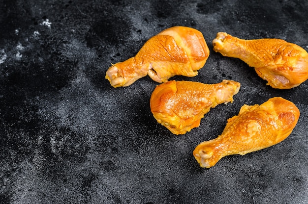 Muslos de muslo de pollo ahumado picante en una mesa de cocina en el cuadro negro. Vista superior.