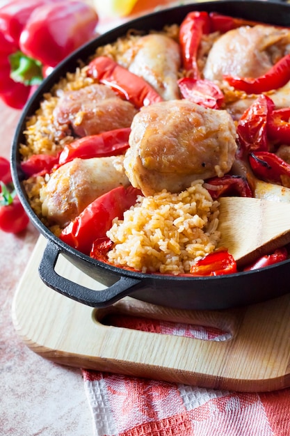 Muslos y muslos de pollo al horno sobre una cama de arroz y pimiento rojo en una cacerola de hierro fundido