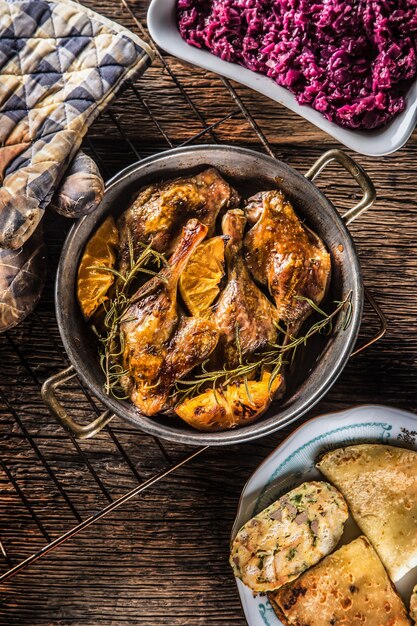 Muslos de pato asado en sartén con naranjas hierbas col lombarda y pankaces de patata.