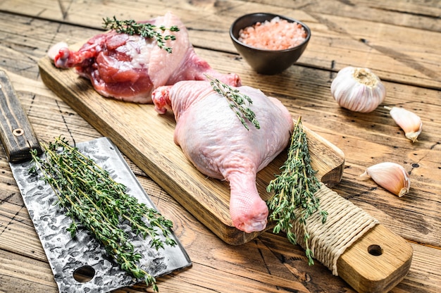 Muslos de pato en tabla de cortar, carne cruda.