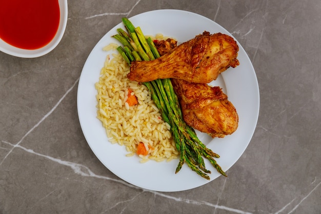 Muslos de pollo al horno con arroz, espárragos y salsa búfalo