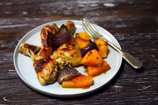 Muslos de pollo al horno con calabaza y cebolla azul en un plato