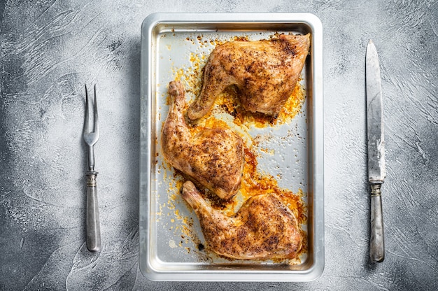 Muslos de pollo asado al horno en una fuente para hornear. Fondo blanco. Vista superior.