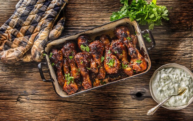 Muslos de pollo asado y asado a la plancha en sartén con salsa tzaziki hierbas y decoración.