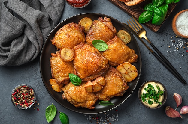 Muslos de pollo con cebolla frita ajo y albahaca fresca sobre un fondo oscuro Vista superior horizontal