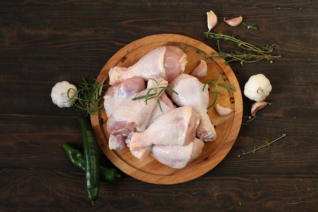 Muslos de pollo crudo con especias en una placa sobre una mesa de madera