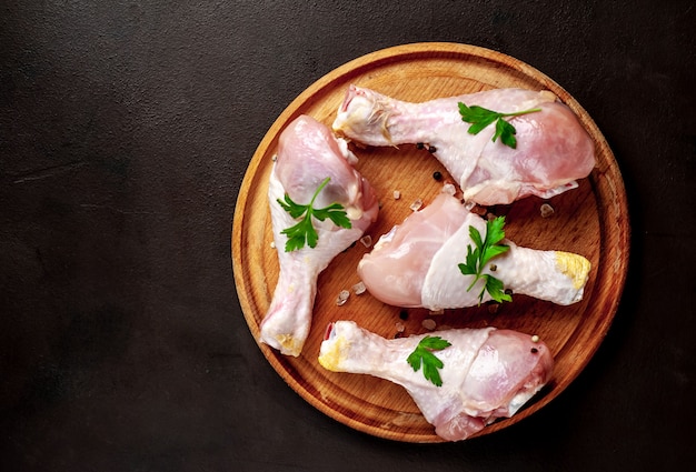 muslos de pollo crudo con especias sobre un fondo de piedra con espacio de copia para su texto