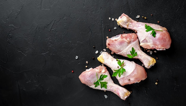 muslos de pollo crudo con especias sobre un fondo de piedra con espacio de copia para su texto