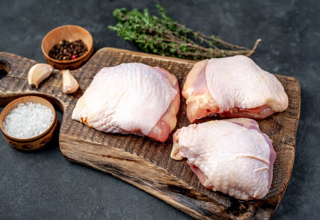 Muslos de pollo crudo con especias sobre un fondo de piedra