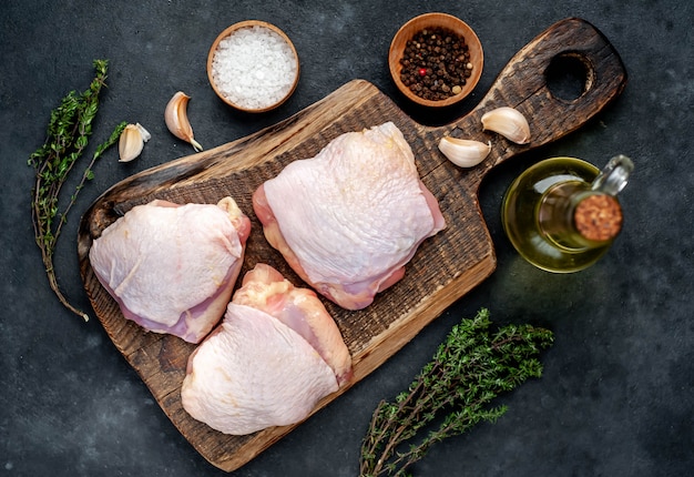 Muslos de pollo crudo con especias sobre un fondo de piedra