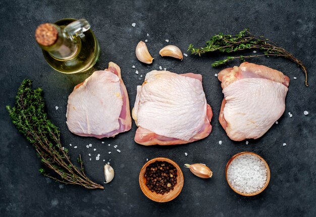 Muslos de pollo crudo con especias sobre un fondo de piedra