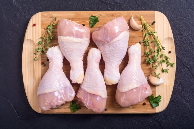 Muslos de pollo crudo con especias sobre tabla de cortar