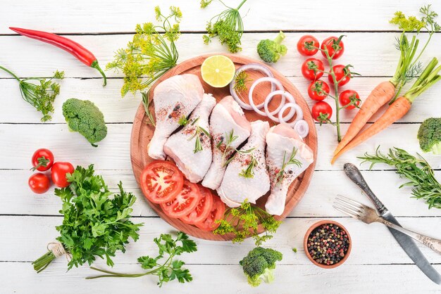 Muslos de pollo crudo con especias y verduras Sobre un fondo de madera Vista superior Espacio de copia