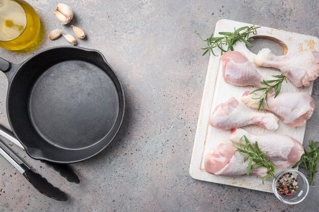 Muslos de pollo crudo con hierbas y especias en la tabla de cortar