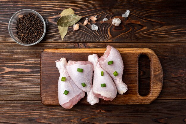 Muslos de pollo crudo en mesa de madera oscura.