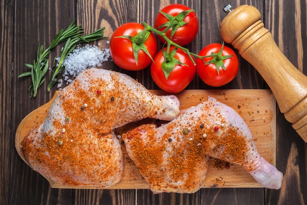 Muslos de pollo crudo sobre una tabla para cortar sobre una mesa de madera