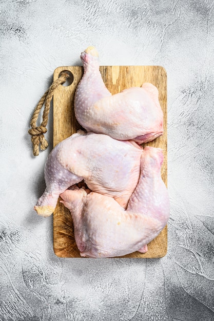 Muslos de pollo crudo en una tabla de cortar. Fondo gris