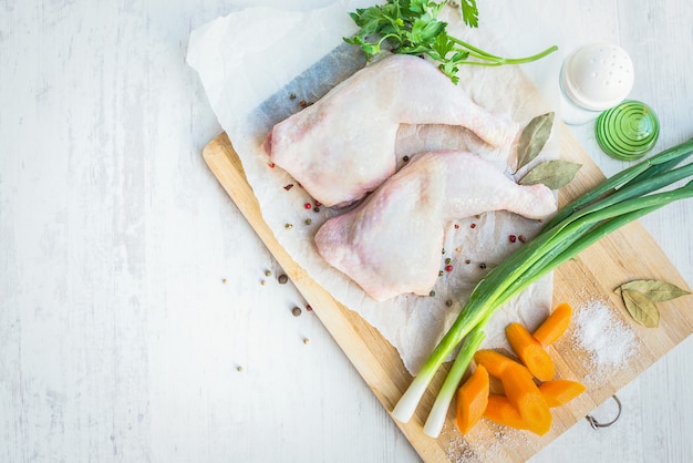 Muslos de pollo crudo con verduras y especias.