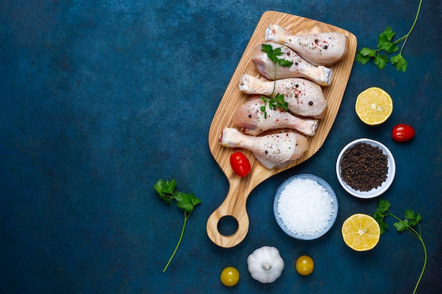 Muslos de pollo con especias y sal listos para cocinar en la tabla de cortar.