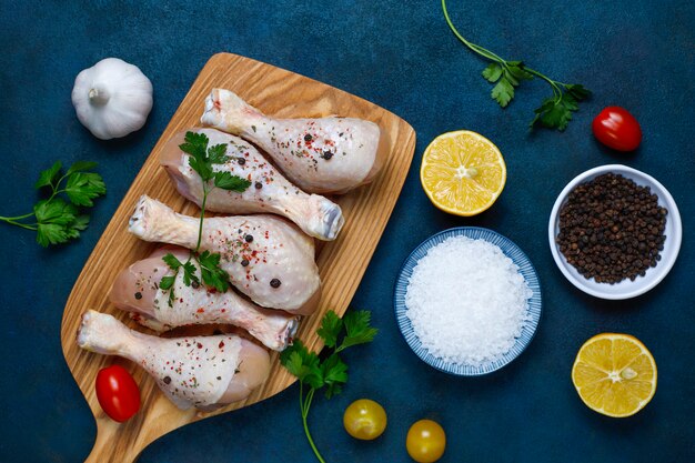 Muslos de pollo con especias y sal listos para cocinar en la tabla de cortar.