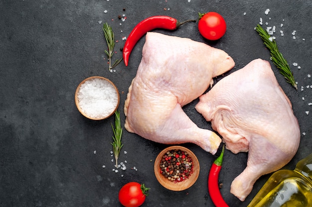 muslos de pollo con especias, tomates, aceite de girasol sobre un fondo de piedra con espacio de copia para su texto