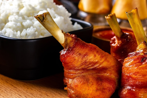 Muslos de pollo frito en un plato de madera con un plato de arroz hervido