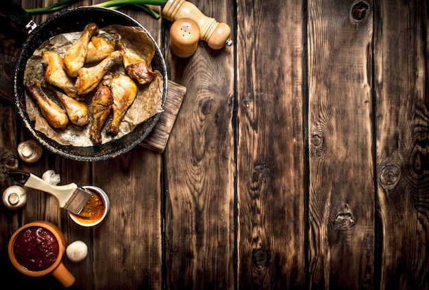 Muslos de pollo frito con salsa de tomate. Sobre una mesa de madera.