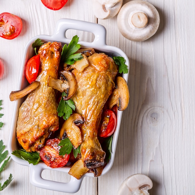 Muslos de pollo fritos con champiñones y tomates.