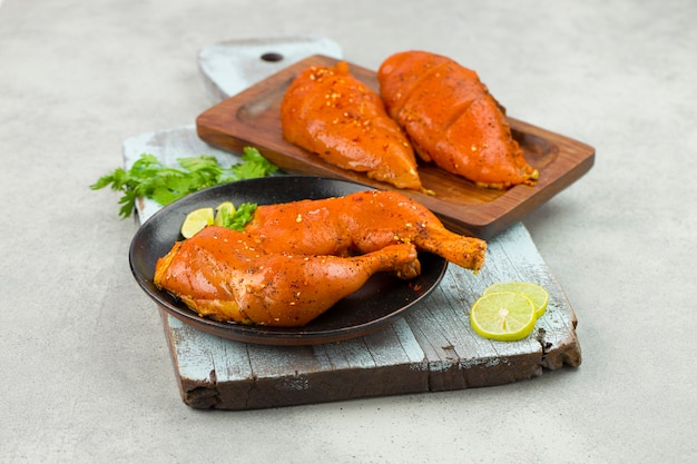 Muslos de pollo marinados y filete de pechuga que se coloca sobre una tabla de cortar pintada