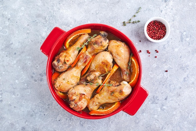 Muslos de pollo con naranjas y tomillo al horno en fuente de horno redonda roja